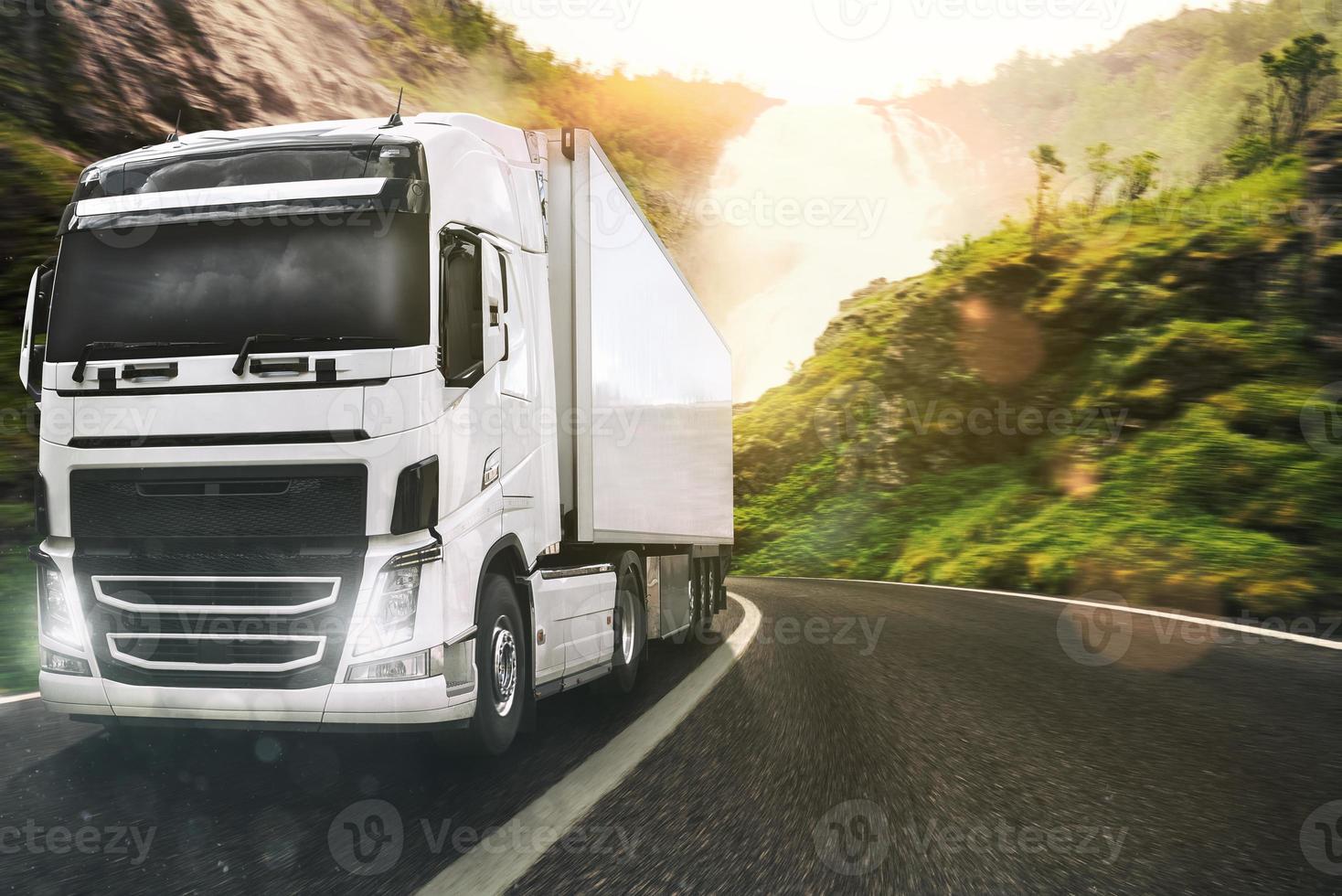 White truck moving on the road in a natural landscape at sunset photo