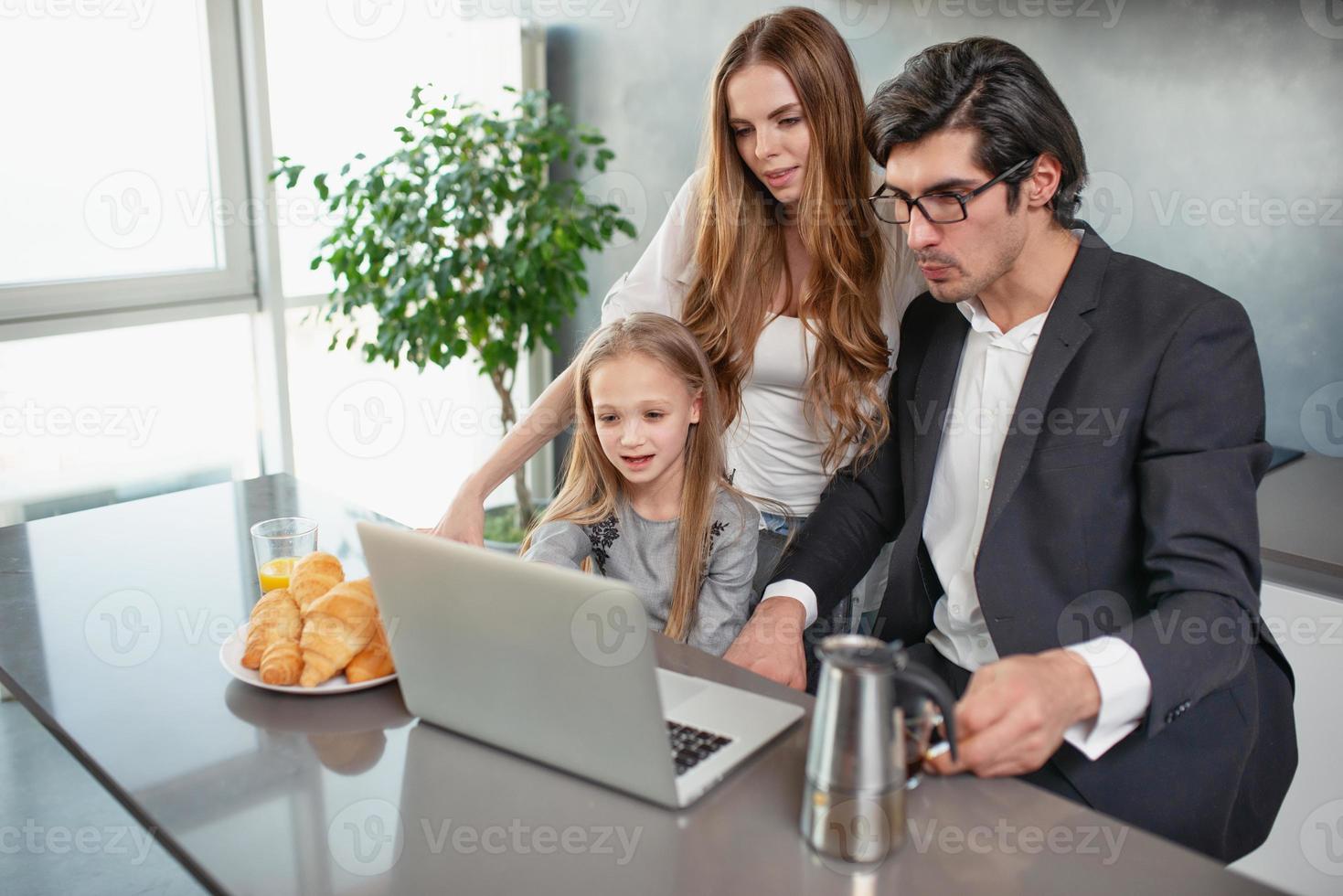 Happy little girl watching a movie on the computer with her father and mother photo