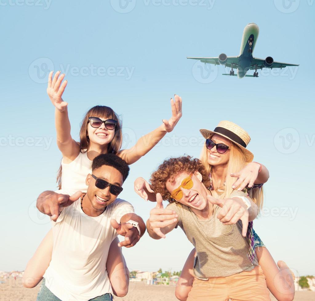 Happy smiling couples playing at the beach with aircraft in the sky photo