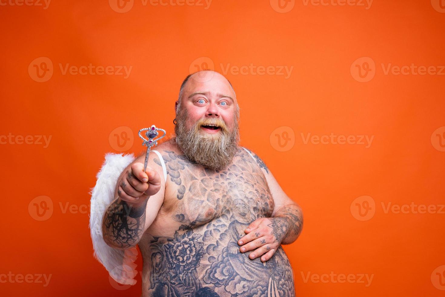 Fat happy man with beard ,tattoos and wings acts like an magic fairy photo