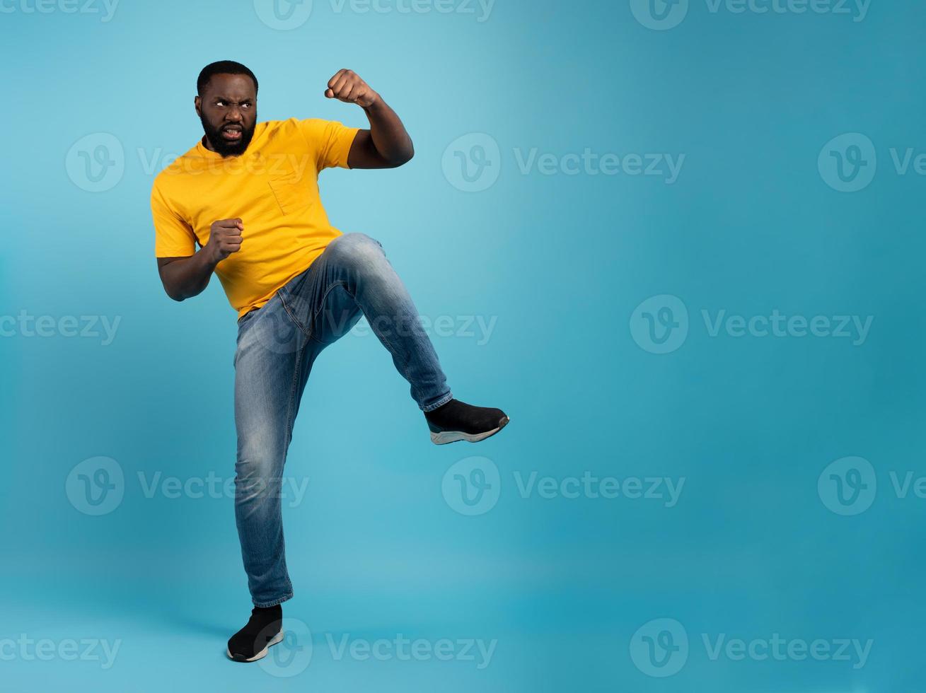 Man is angry and fights with kicks. Blue background photo