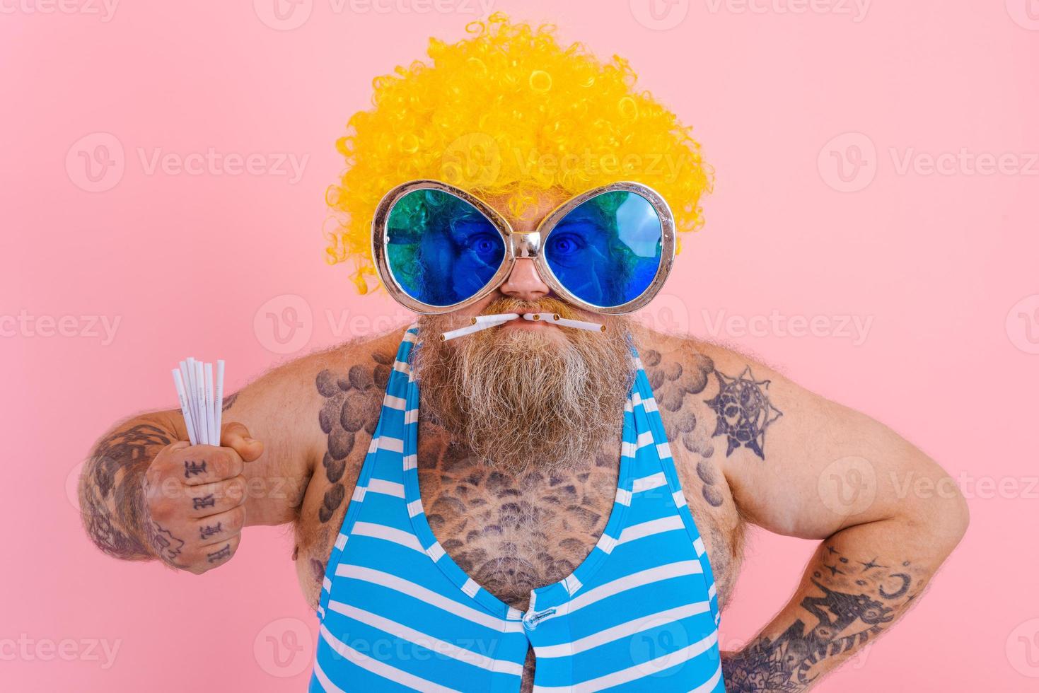 Fat angry man with beard and wig smokes cigarettes photo