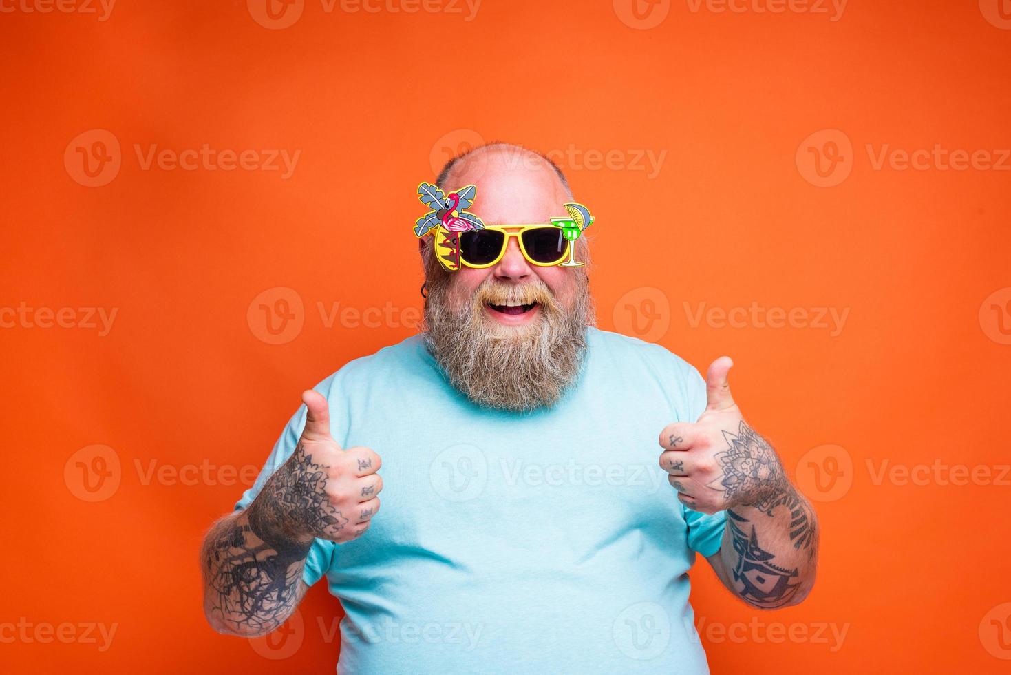 Fat happy man with beard, tattoos and sunglasses is ready for the summer photo