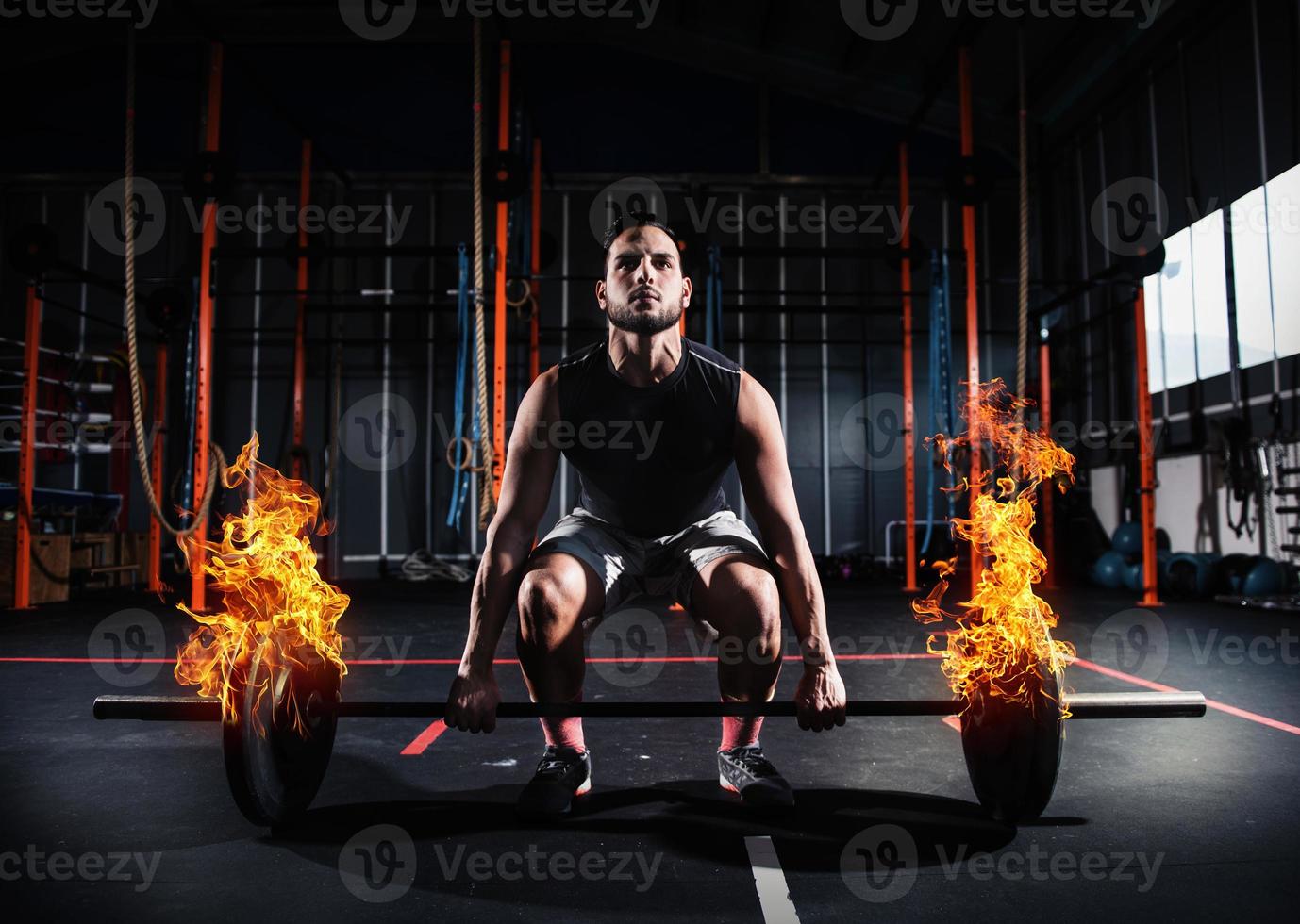 Athletic man works out at the gym with a fiery barbell photo