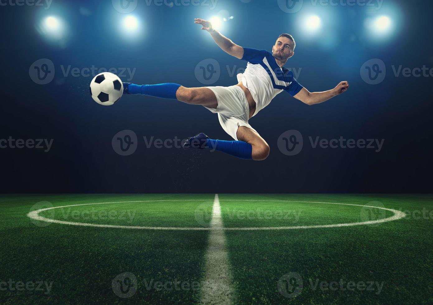 Soccer striker hits the ball with an acrobatic kick photo