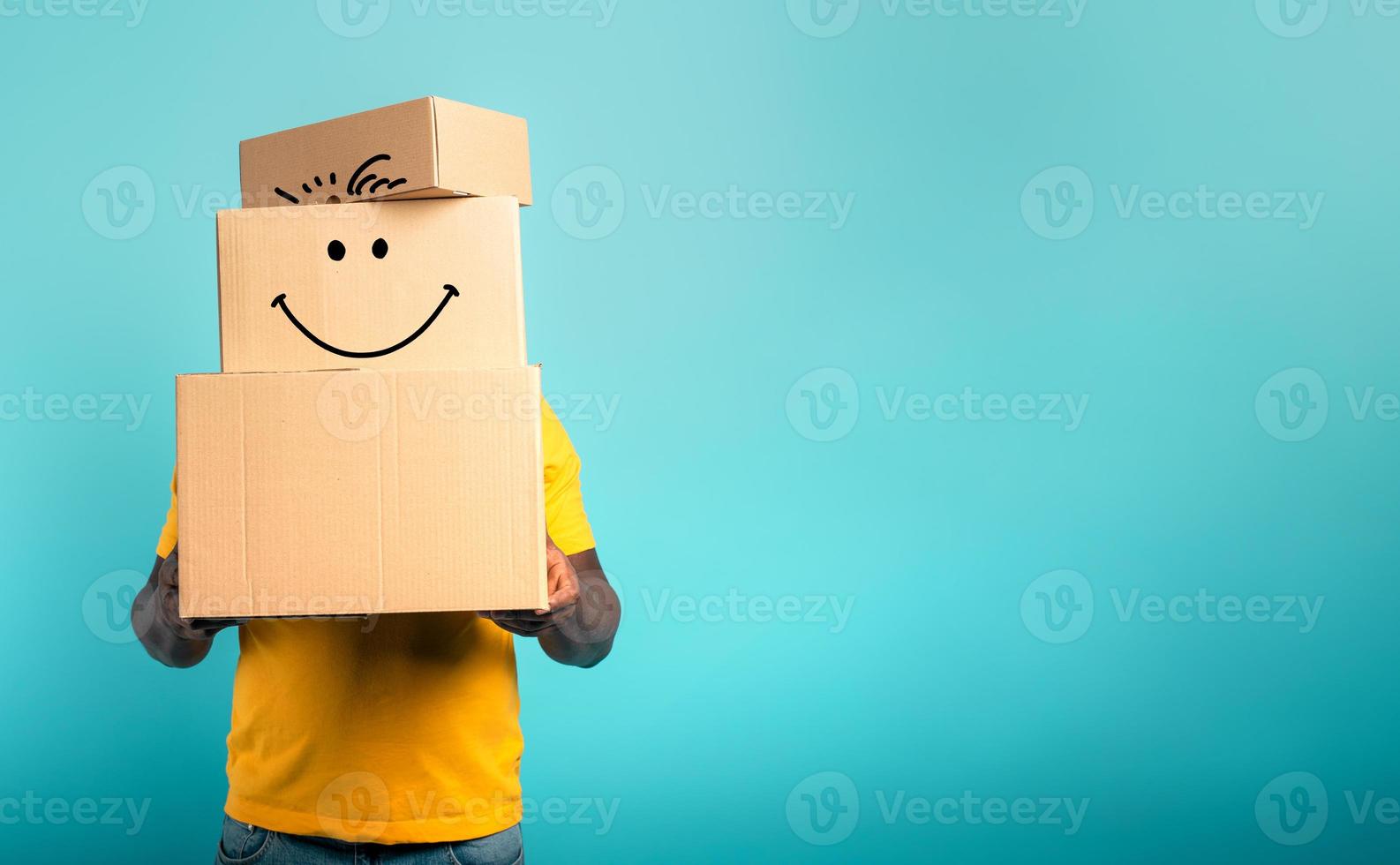 Man is hidden by too many received packages. Cyan background photo