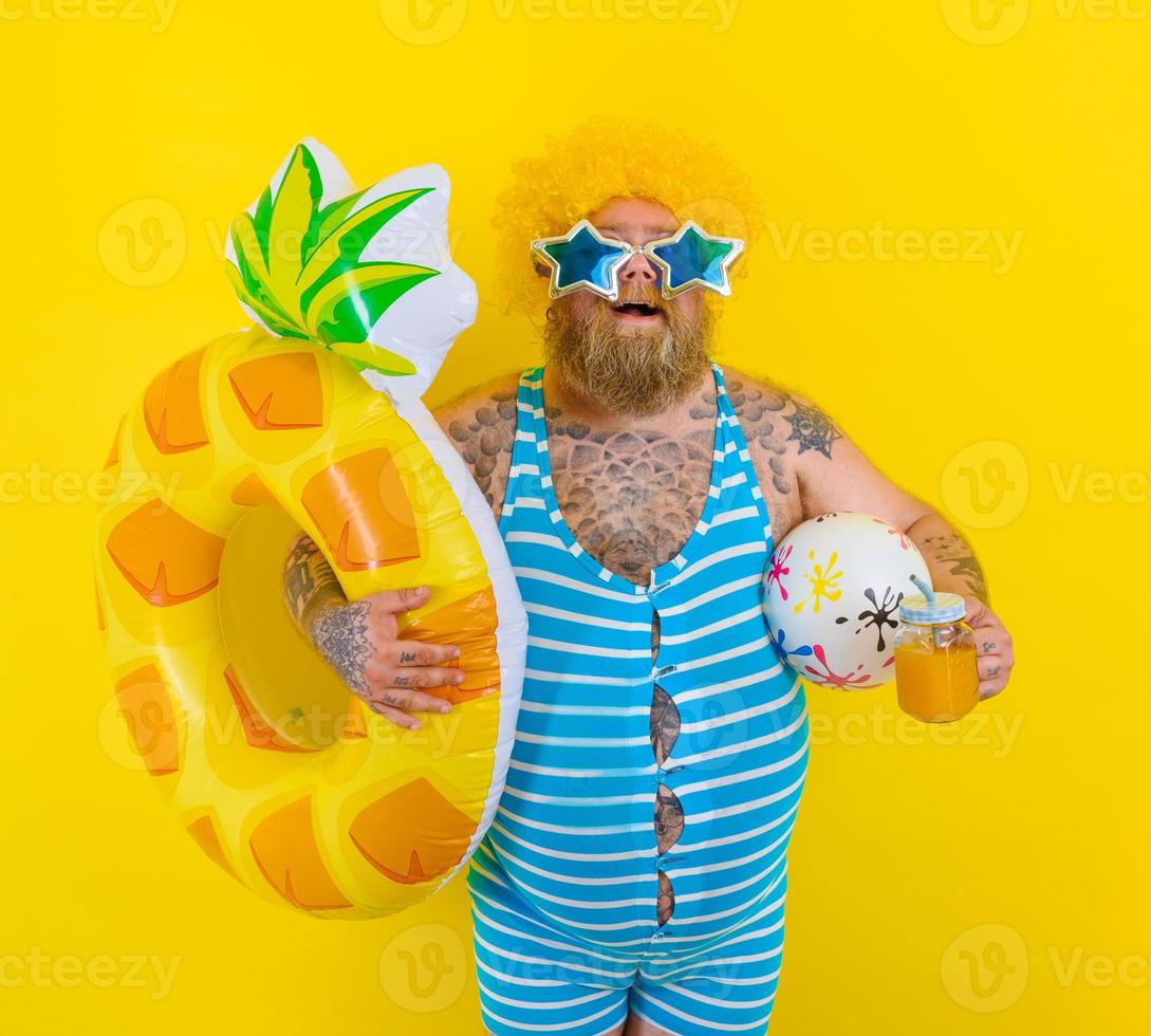 Fat amazed man with wig in head is ready to swim with a donut lifesaver photo