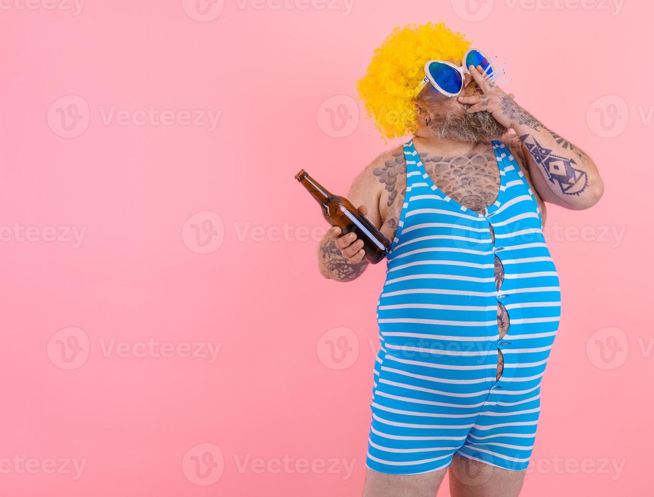 Fat man with beard and wig smokes cigarettes and drinks beer photo
