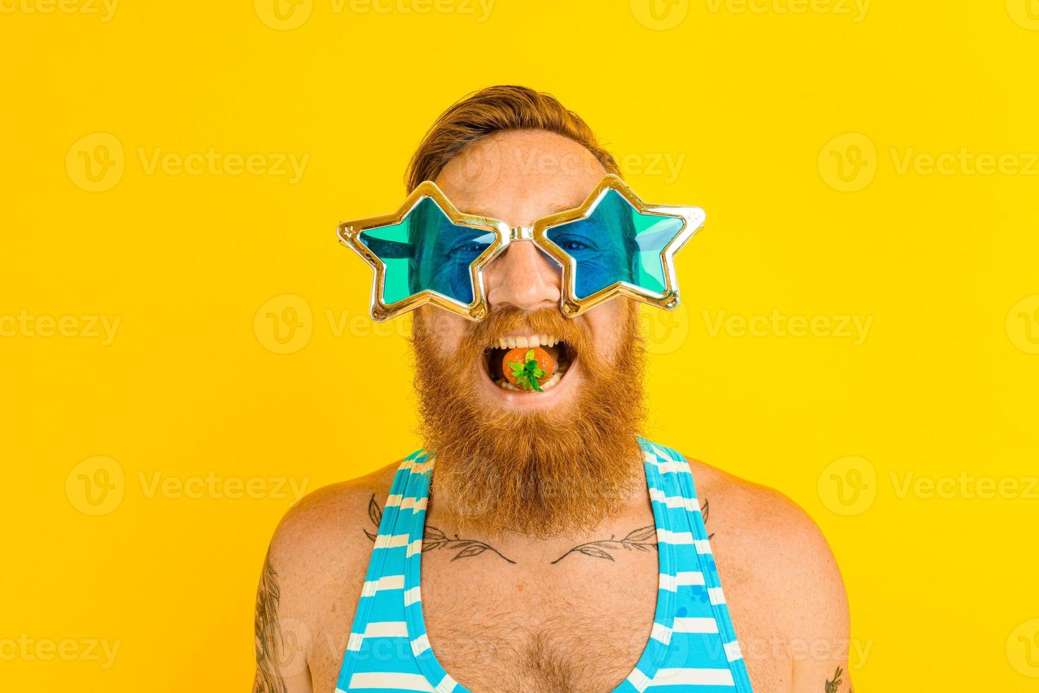 man with beard and sunglasses eats a strawberry photo