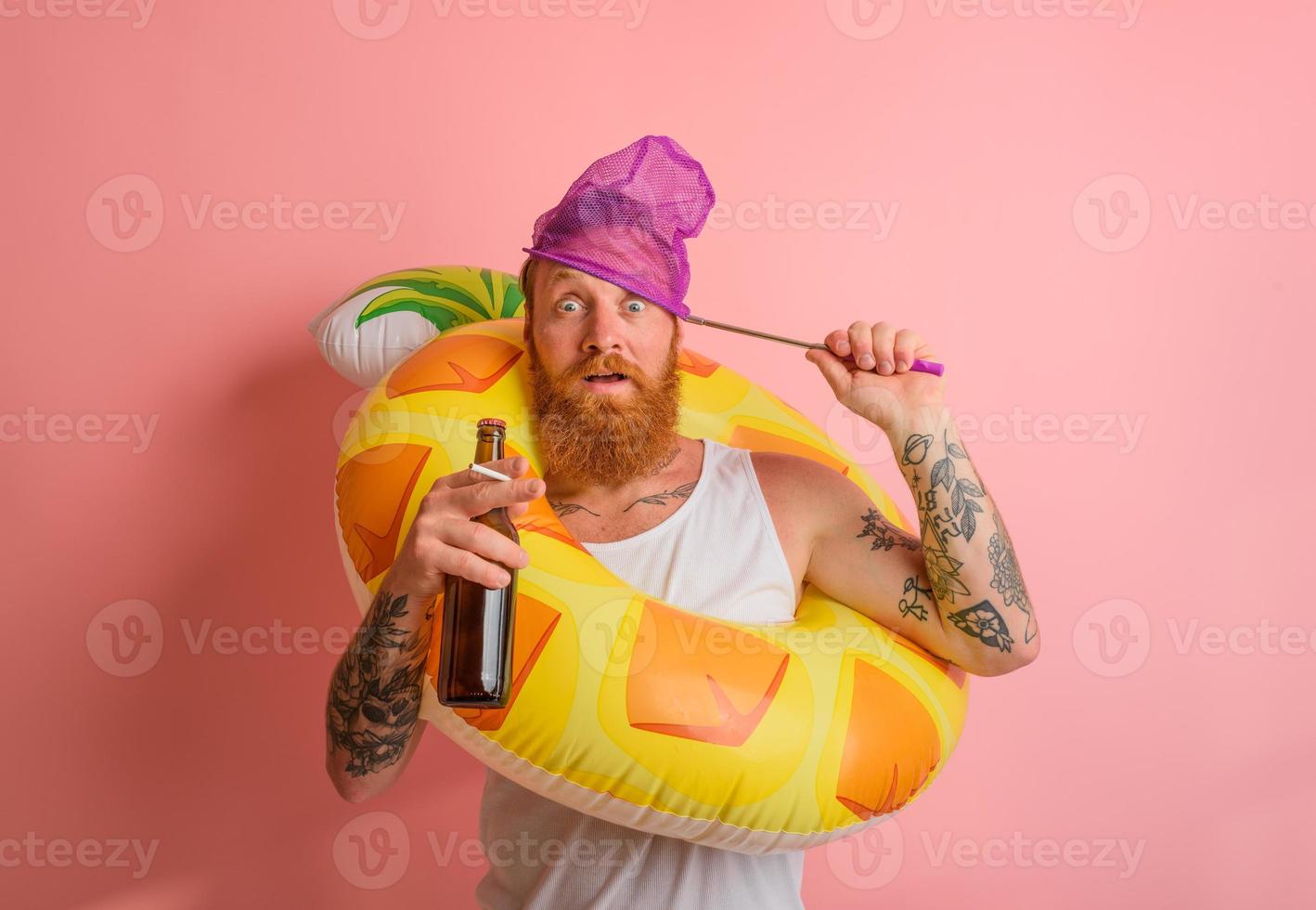 Amazed man is ready to swim with a donut lifesaver with beer and cigarette in hand photo
