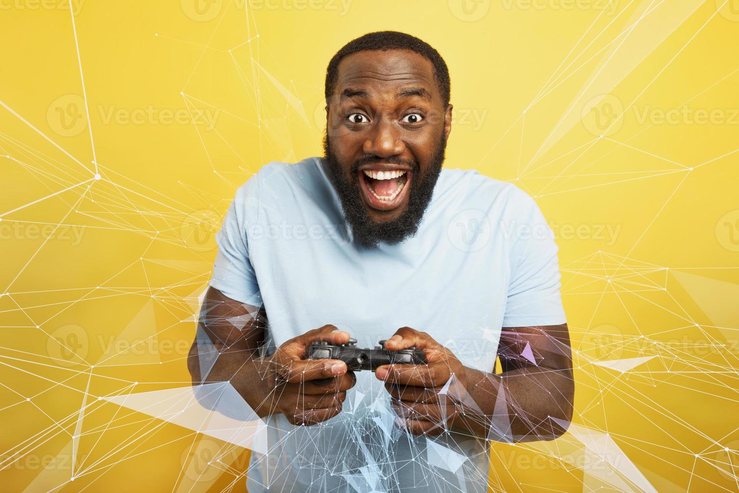 Happy man plays with a videogame on yellow background photo