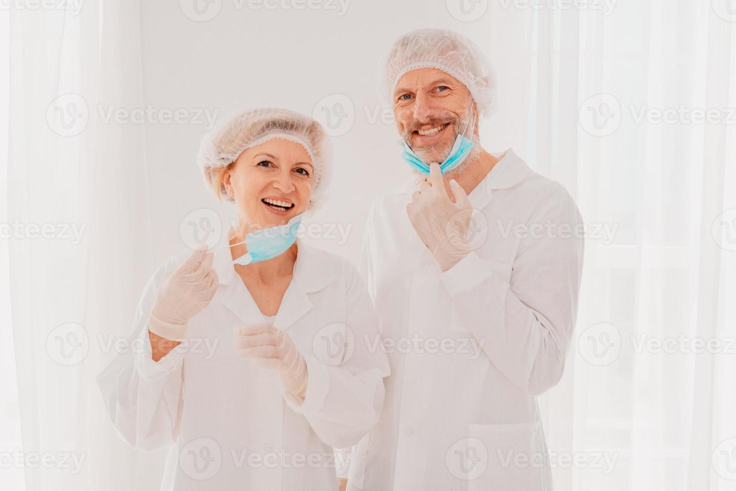 sonriente doctores con cara máscara son contento a trabajo en contra covid-19 foto