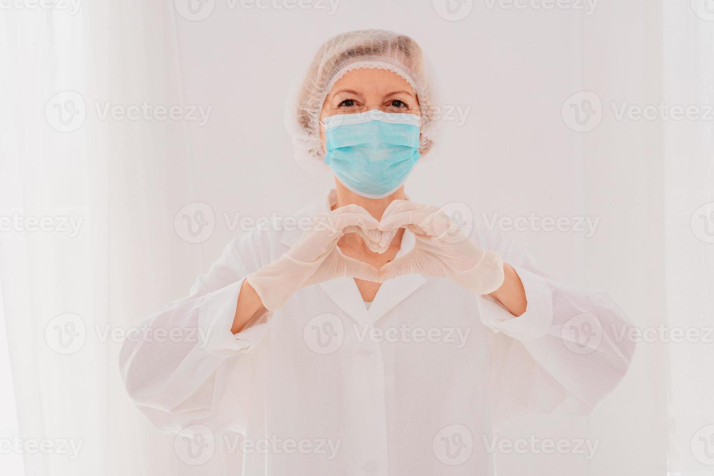 médico con máscara hace un corazón con su manos foto