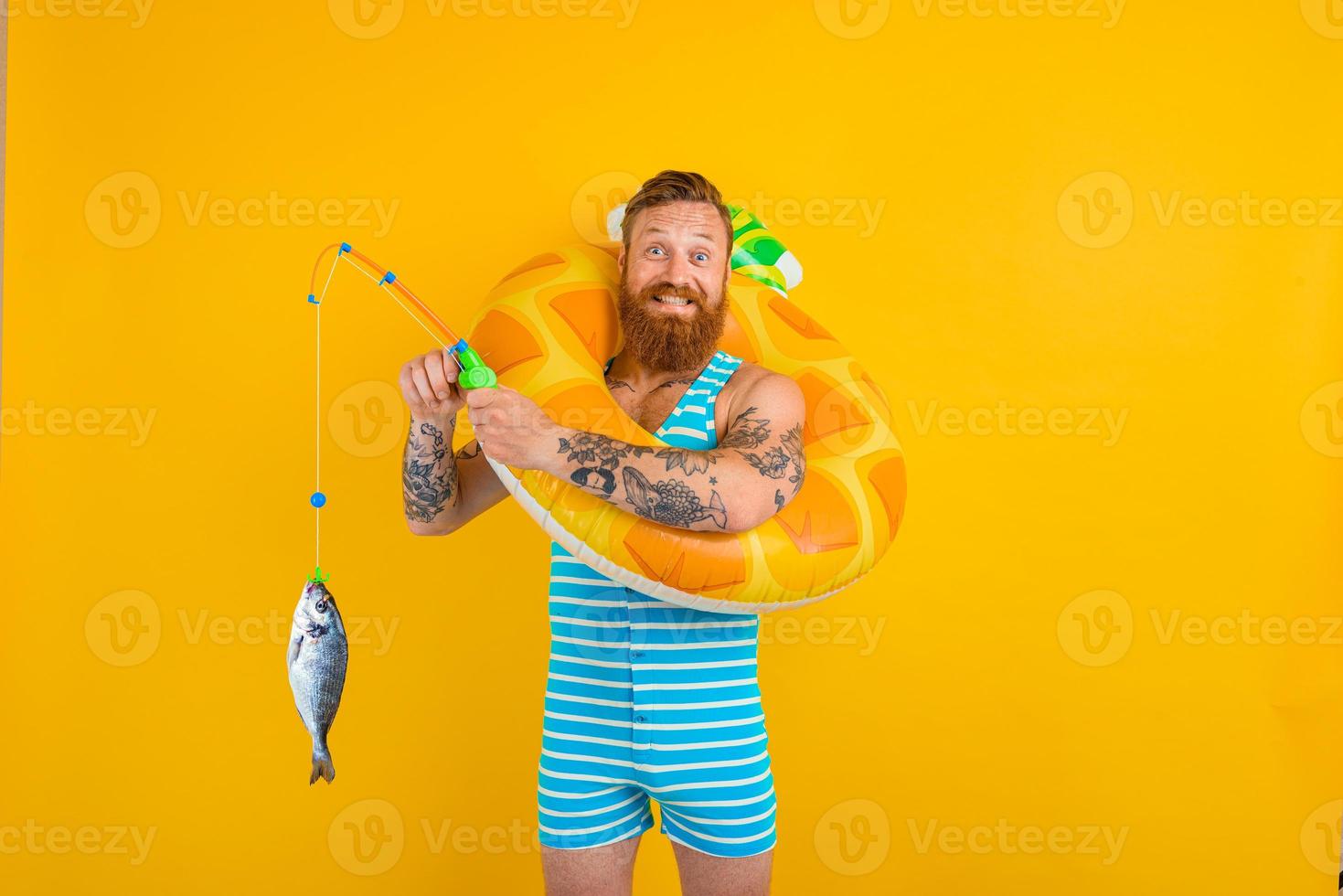 Happy man with beard and inflatable donut catches fish photo