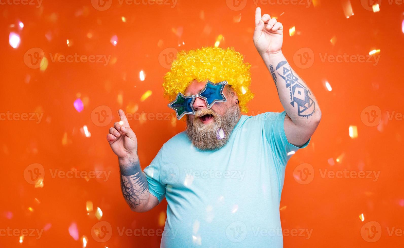 grasa hombre con barba, tatuajes y Gafas de sol bailes música en un disco foto