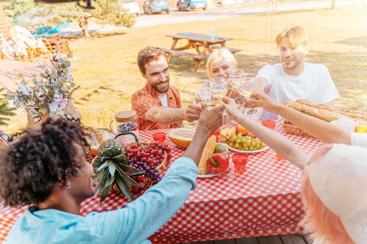 amigos tener un picnic y brindis con vino foto