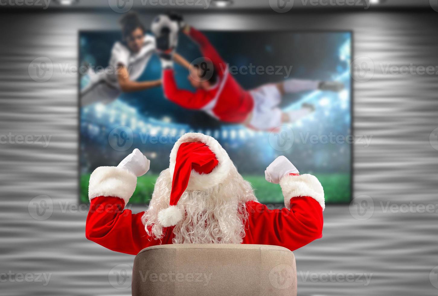 Joyful Santa Claus, soccer fan, watches a game on television photo