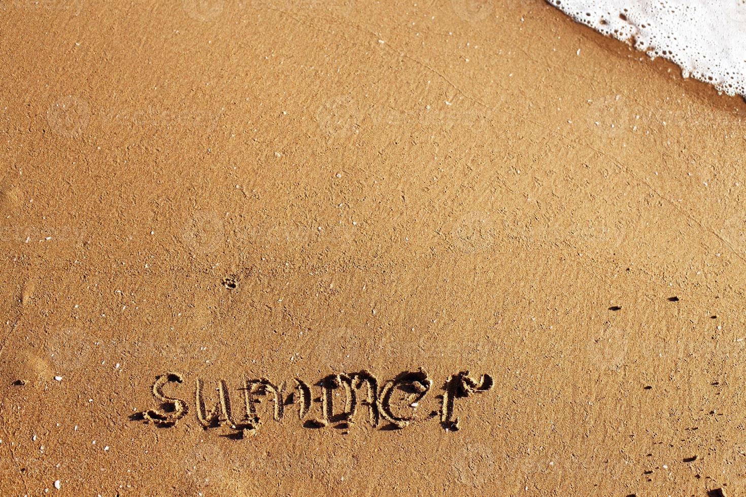 Word summer handwritten on the sandy beach with wave and copy space photo