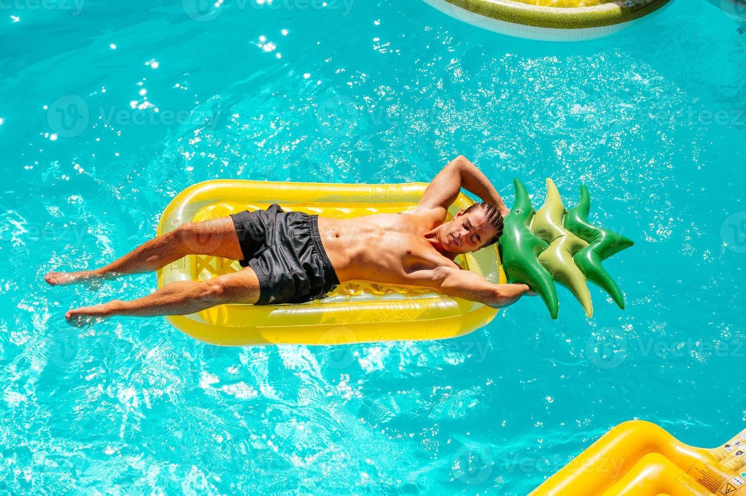 hombre en traje de baño en el piscina consiguiendo un bronceado foto