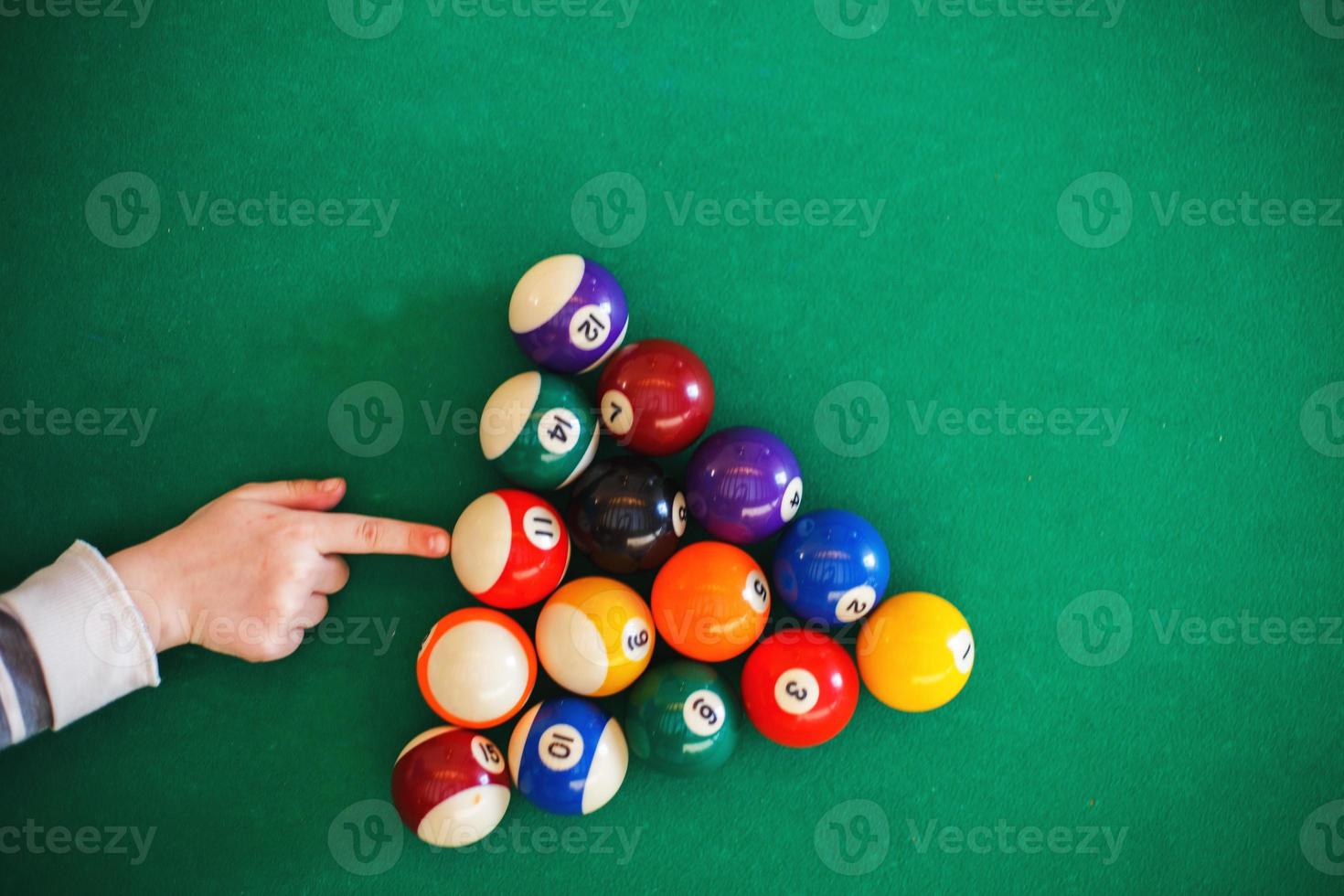 balls on a billiard table in a triangle. child playing billiards photo