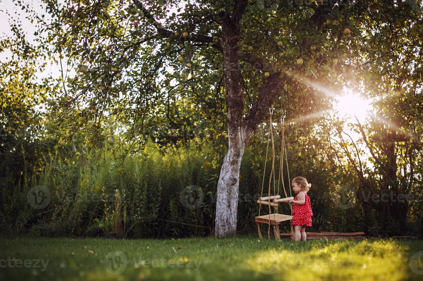 girl in the garden playing with swings. baby playing in the garden photo