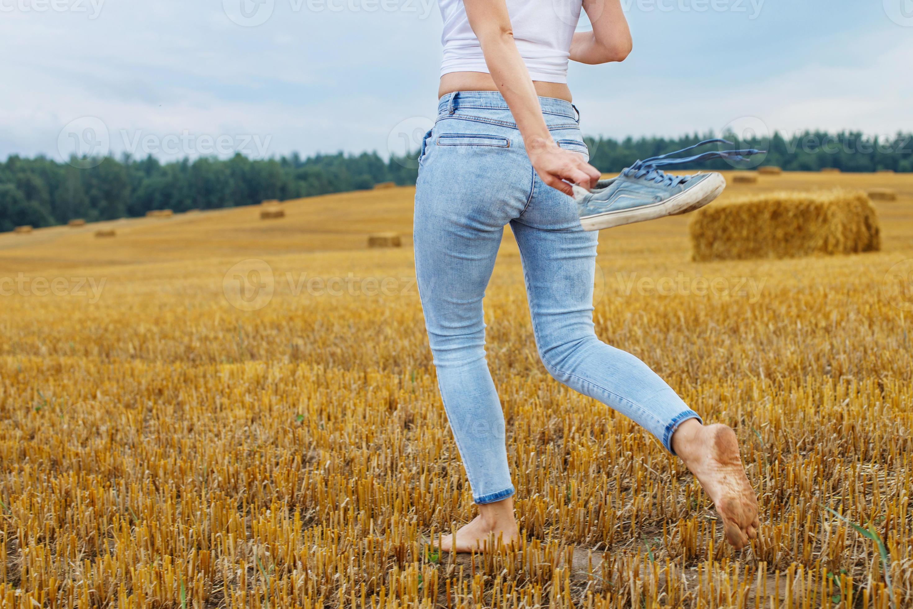 https://static.vecteezy.com/system/resources/previews/020/727/085/large_2x/barefoot-girl-with-sneakers-in-hand-walking-in-the-agricultural-field-with-haystack-and-bales-photo.JPG