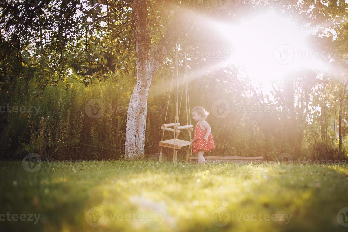 girl in the garden playing with swings. baby playing in the garden photo