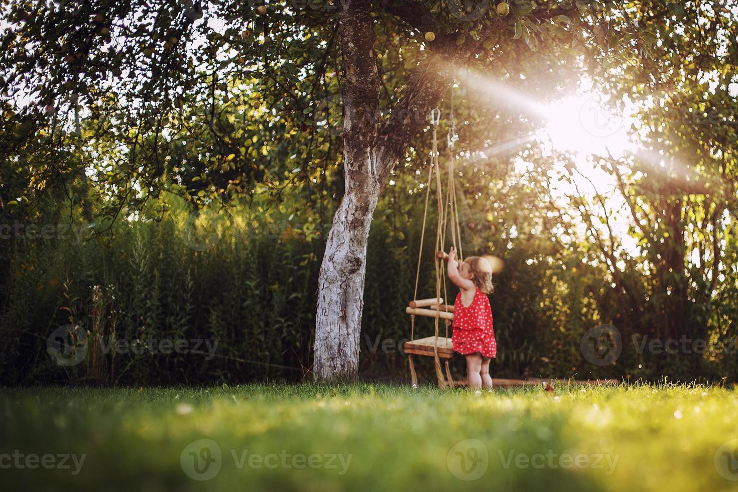 girl in the garden playing with swings. baby playing in the garden photo