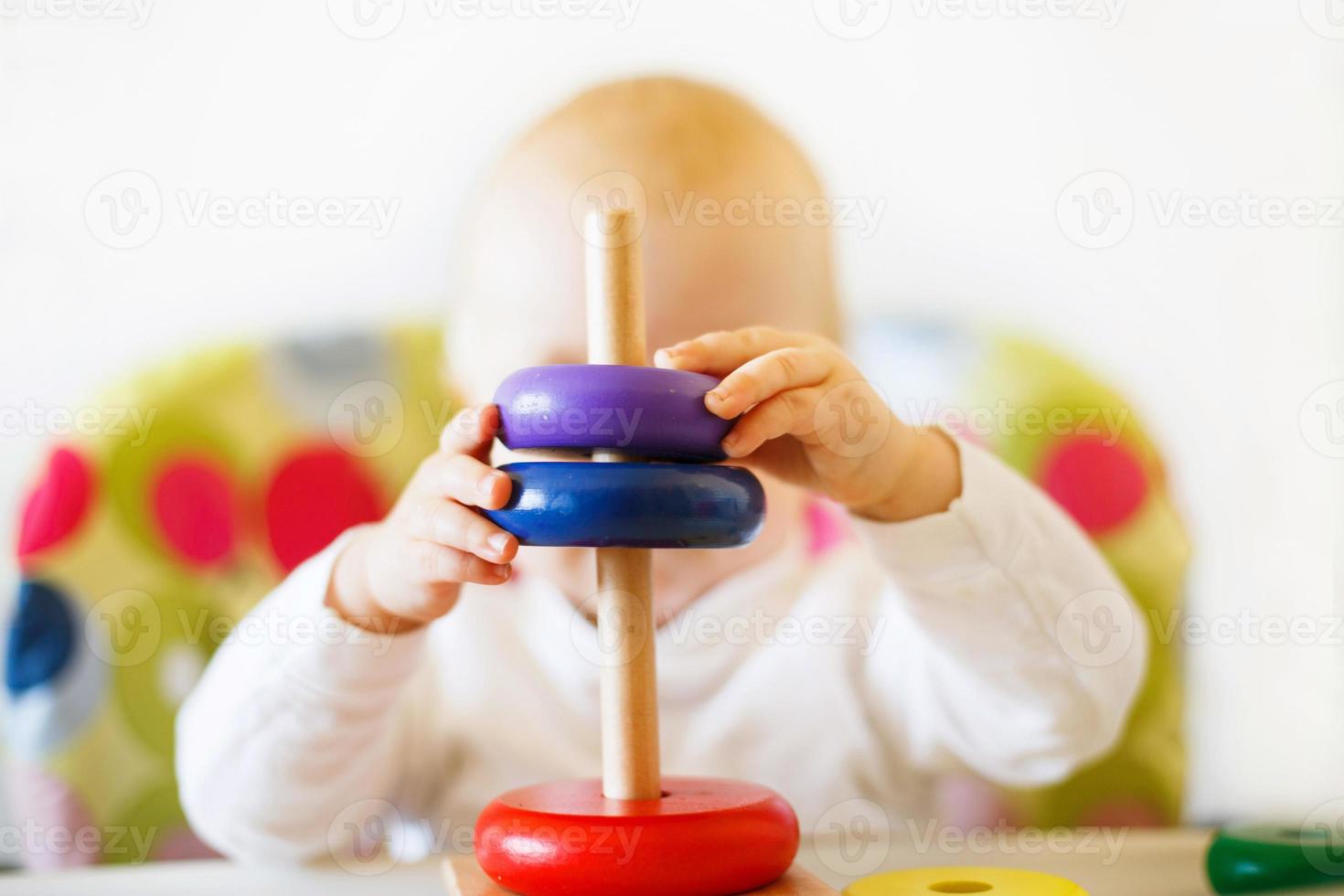 the kid plays the pyramid. child playing with wooden toys photo