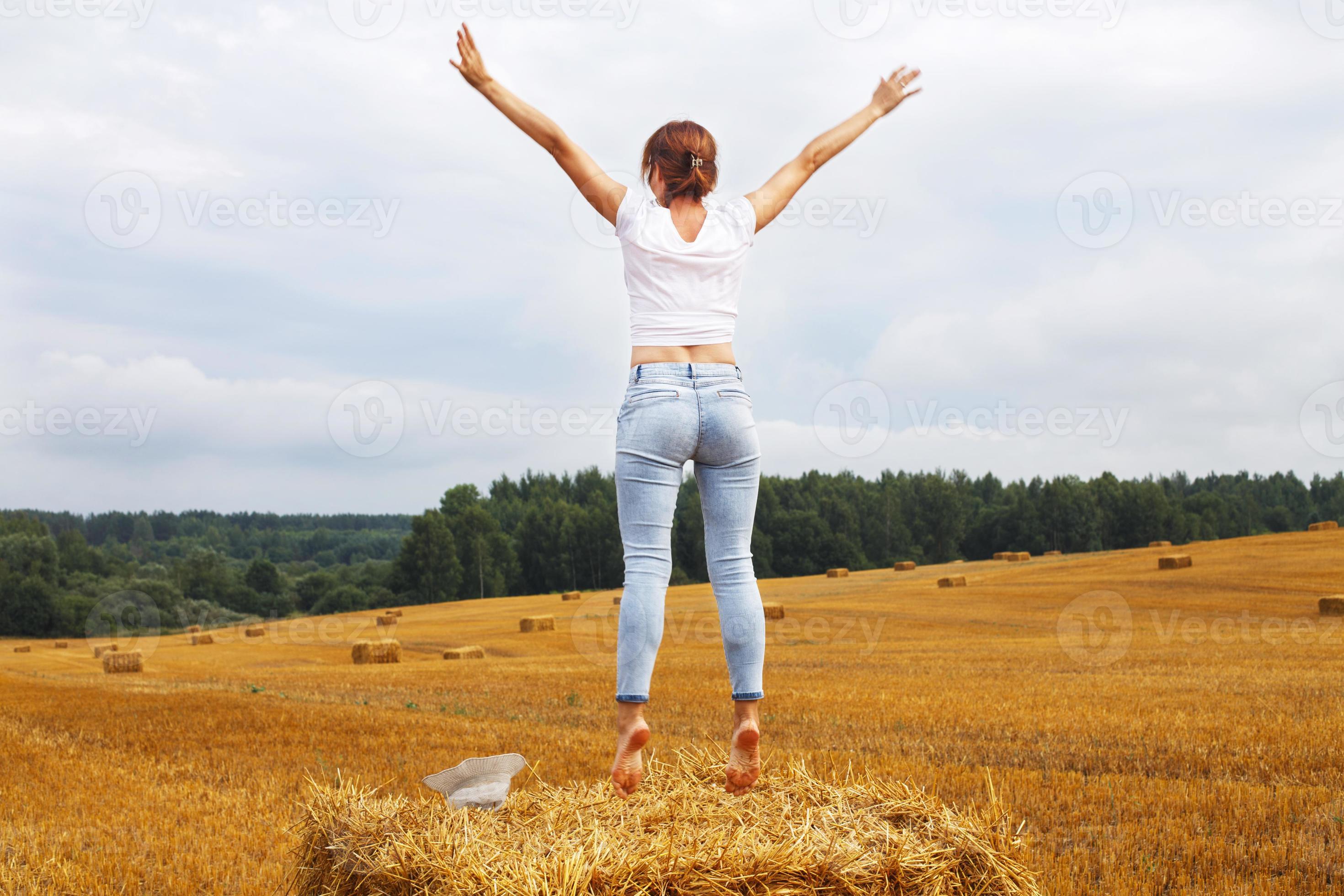 https://static.vecteezy.com/system/resources/previews/020/727/554/large_2x/girl-with-straw-hat-stands-on-a-haystack-on-a-bale-in-the-agricultural-field-after-harvesting-photo.JPG