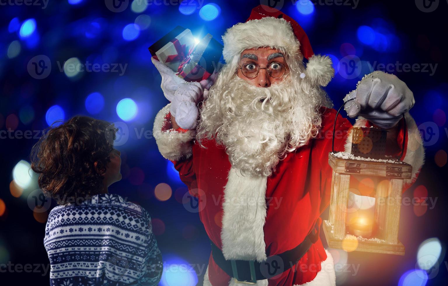Papa Noel claus es dando un presente para Navidad a un pequeño chico foto
