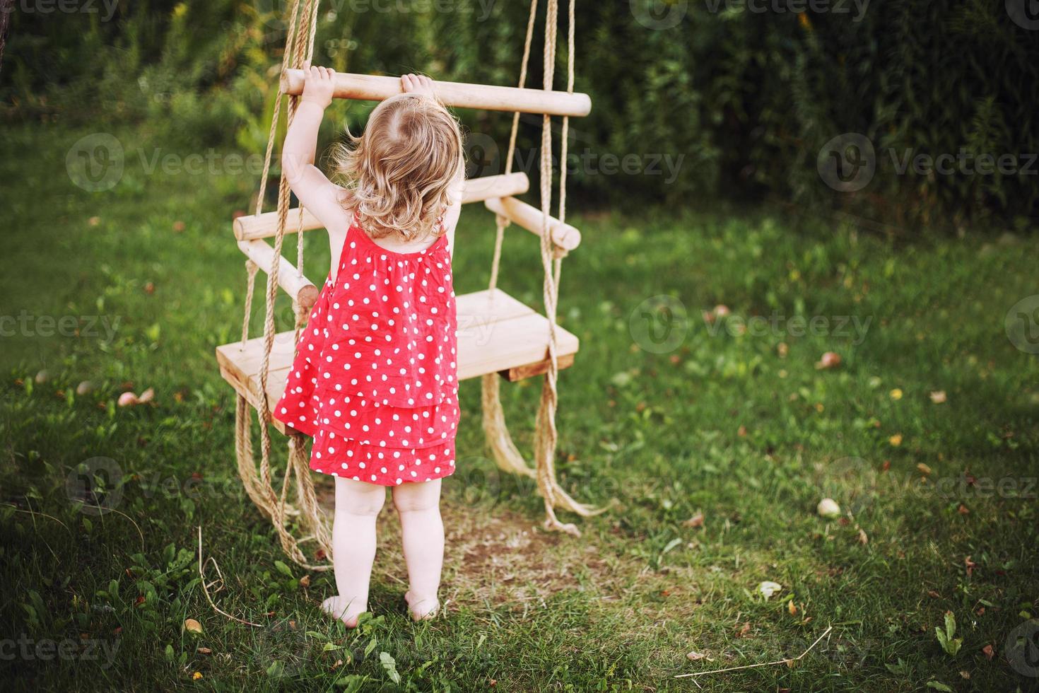 girl in the garden playing with swings. baby playing in the garden alone photo