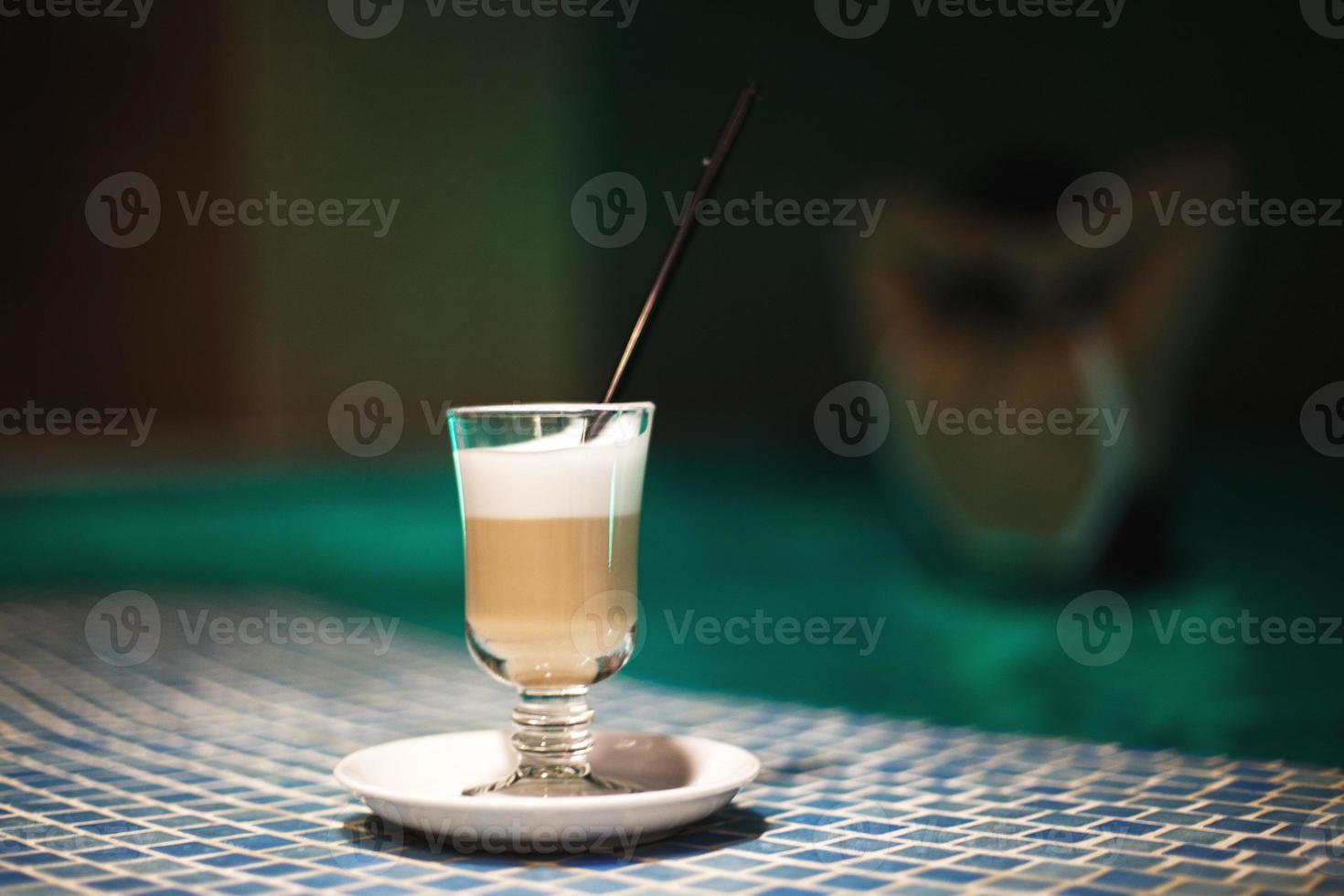 a cup of coffee in the pool and a girl in the background photo