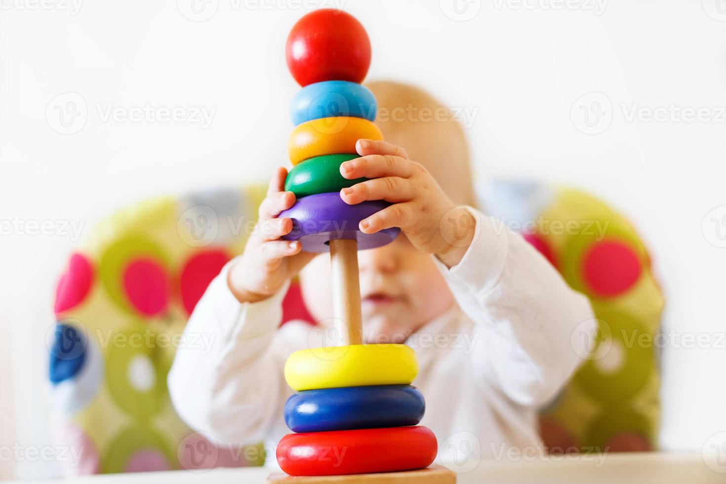 the kid plays the pyramid. child playing with wooden toys photo