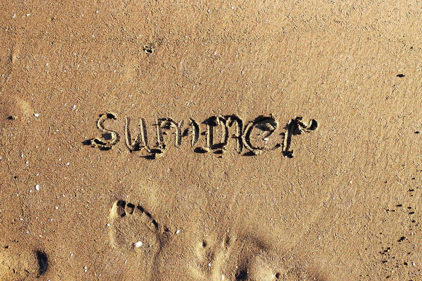 Word summer handwritten on the sandy beach and footprint with copy space photo