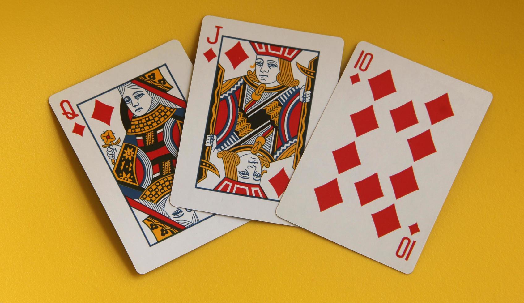 Jakarta, Indonesia - February 24th, 2023 - Queen, Jack, and diamond 10. Common playing cards for poker, gambling, or just for fun entertainment purposes. Object photo isolated on yellow background.