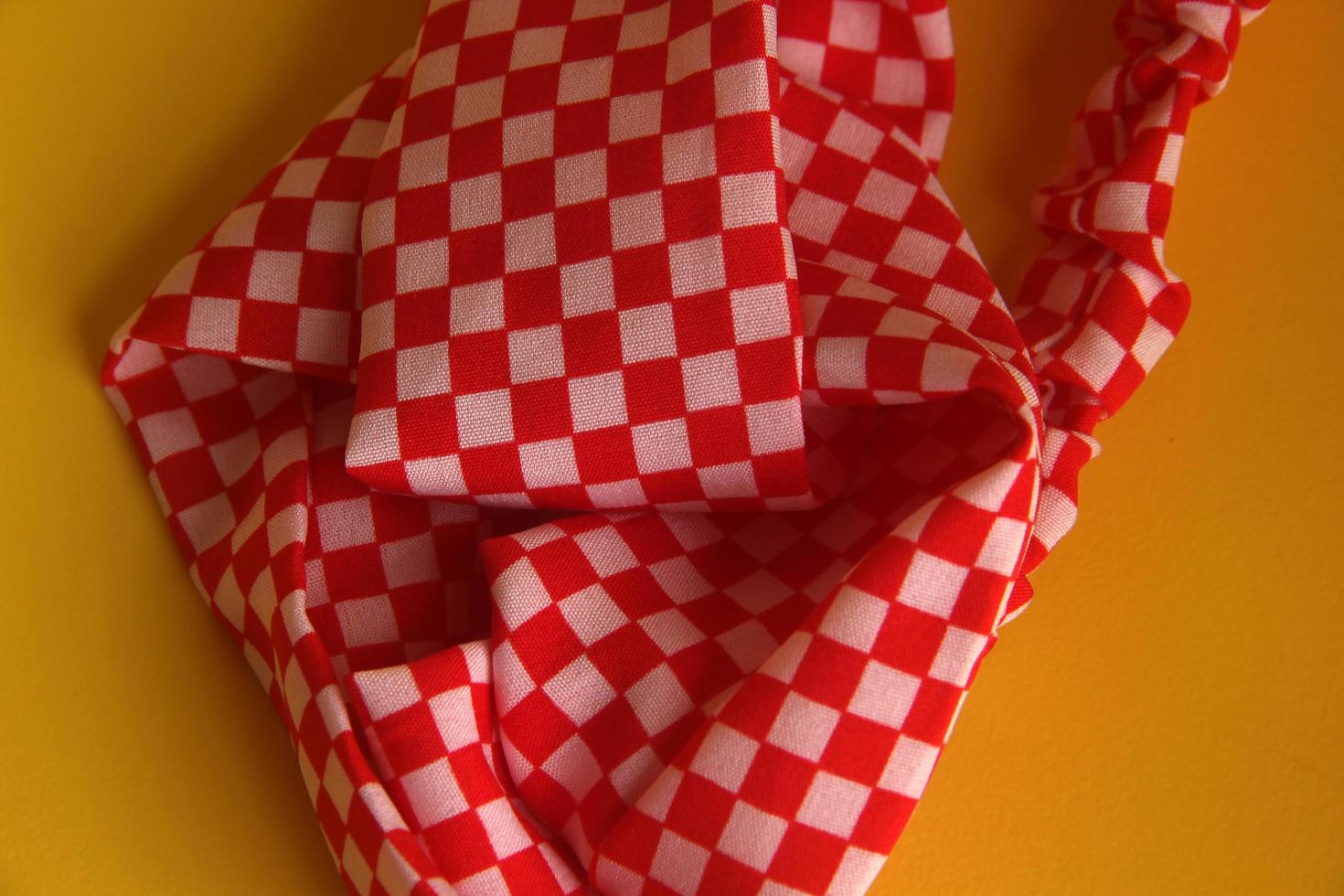 Cool red and white checkered pattern women hair accessories band. Fashion object photo isolated on yellow background.