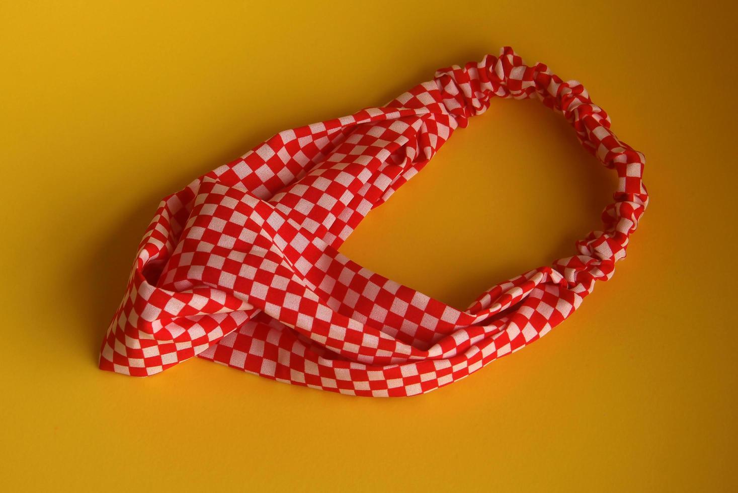 Cool red and white checkered pattern women hair accessories band. Fashion object photo isolated on yellow background.