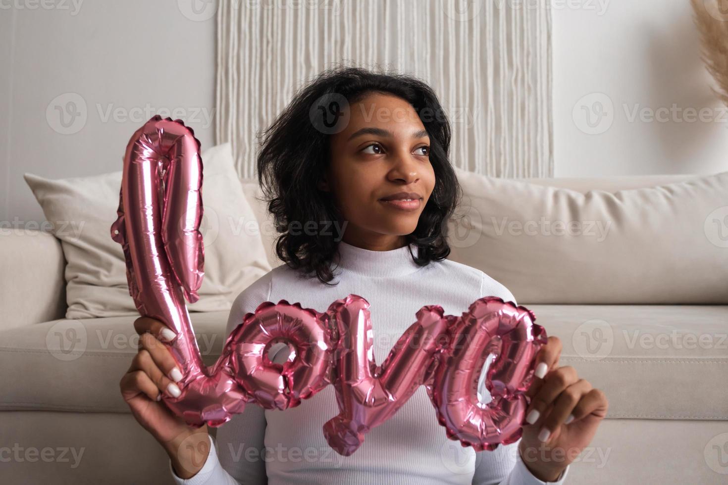 Valentines day portrait of african woman with love shaped balloon. 14 february concept photo