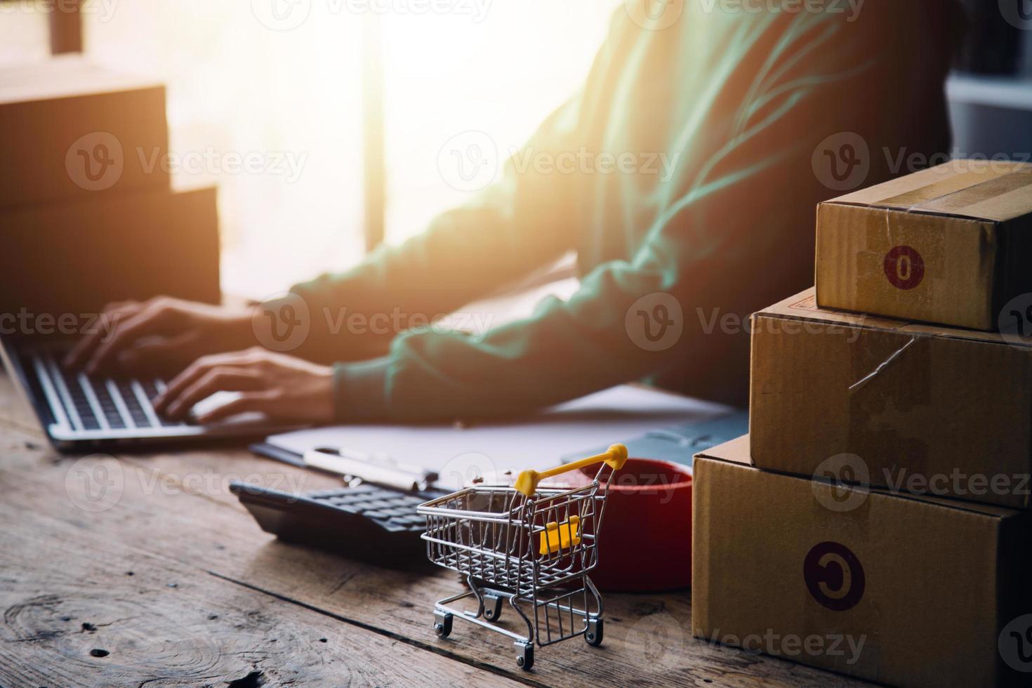 Startup SME small business entrepreneur of freelance Asian woman wearing apron using laptop and box to receive and review orders online to prepare to pack sell to customers, online sme business ideas. photo