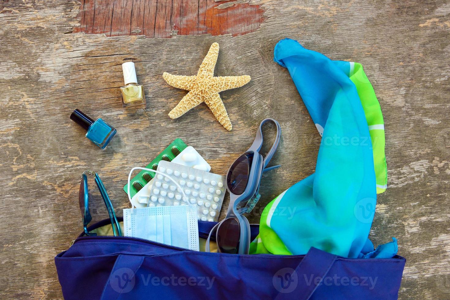 Beach bag, women's accessories, pills and protective medical mask on old wooden background. Top view. photo
