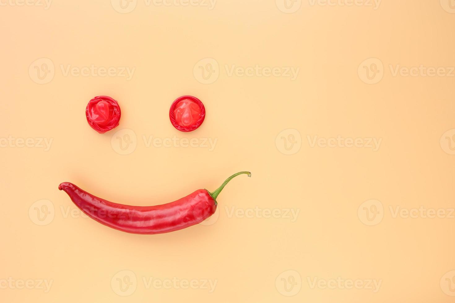 Red hot pepper with condom on a beige background. Space for text. photo