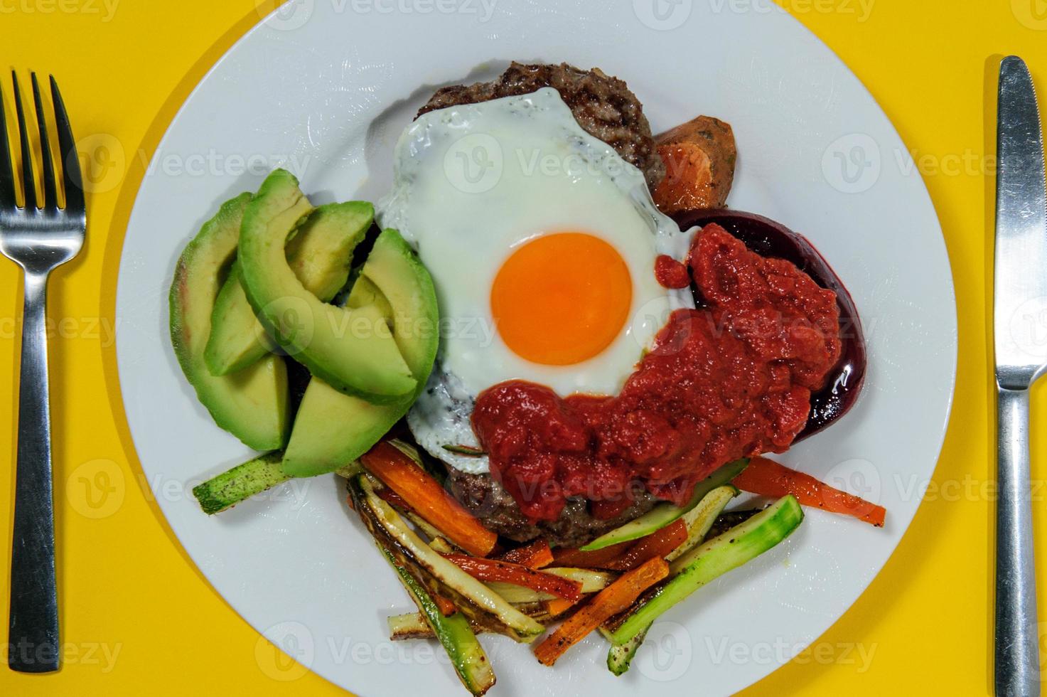Tasty breakfast. Sunny side up eggs with green asparagus, fried bacon and garlic dip served on black plate on wooden table photo