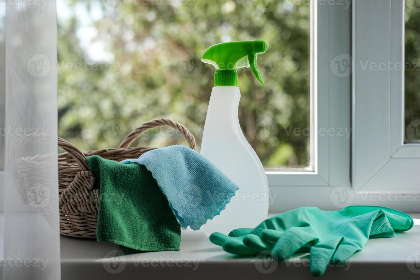 Cleaning agent, wipes and rubber gloves in a basket on the windowsill. General cleaning concept photo