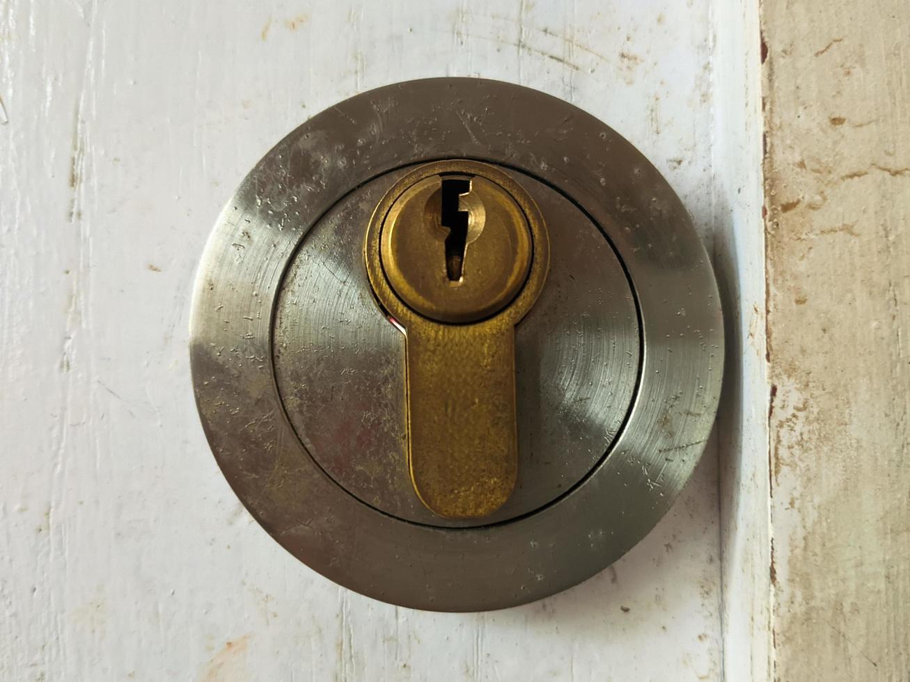 Close-up of a round steel keyhole, looking old and rusty, on the old white door photo