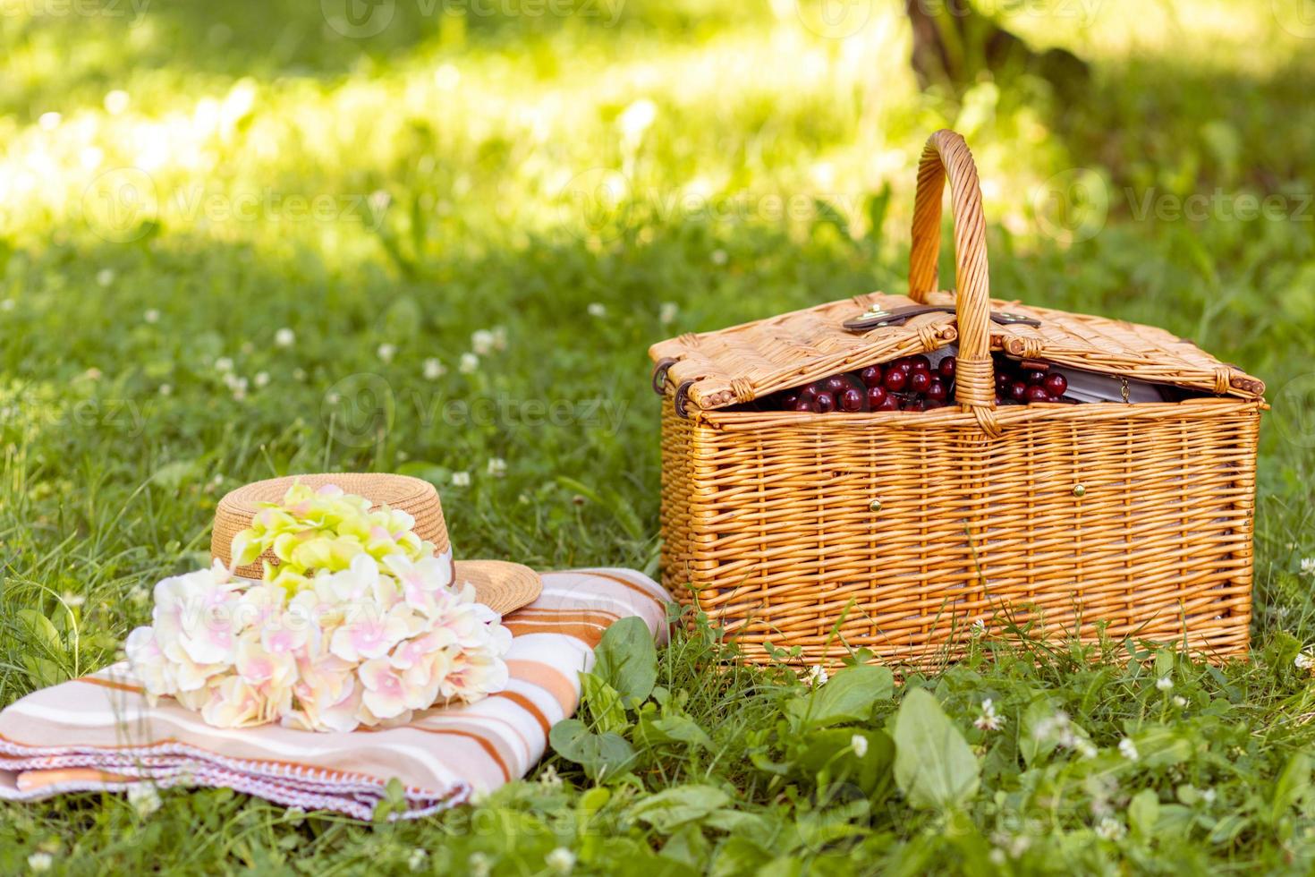 Cozy picnic in the park. Summer picnic with picnic basket with summer flowers, hat and plaid photo