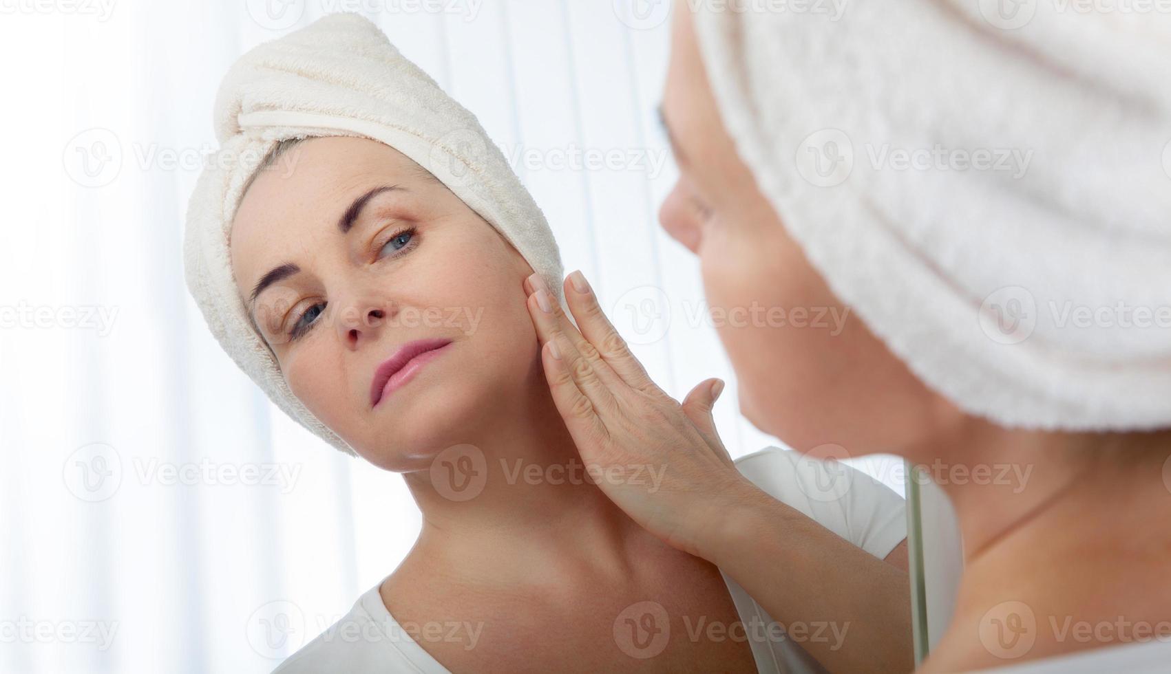 Forty years old woman looking at wrinkles in mirror. Plastic surgery and collagen injections. Makeup. Macro face. Selective focus on the face. photo