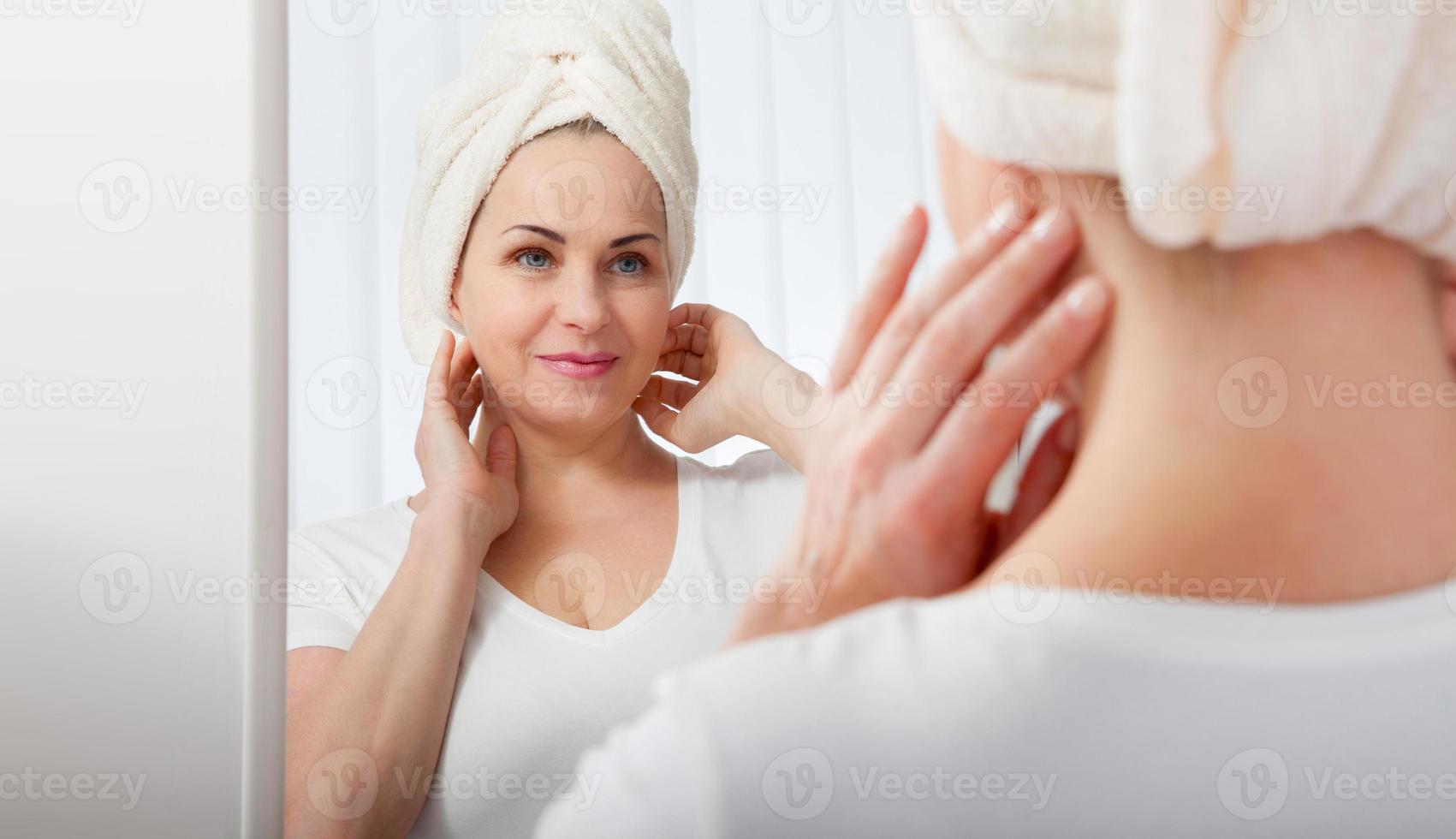 Forty years old woman looking at wrinkles in mirror. Plastic surgery and collagen injections. Selective focus on the face. photo