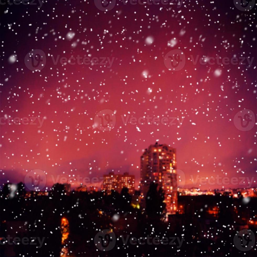 Blurred lights of city at night in winter in snowy weather. Snow bokeh texture on city background night winter. photo