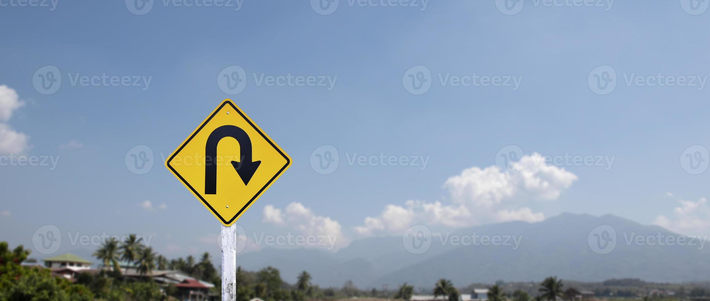 Traffic sign, right U turn sign on cement pole beside the rural road with white cloudy bluesky background, copy space. photo